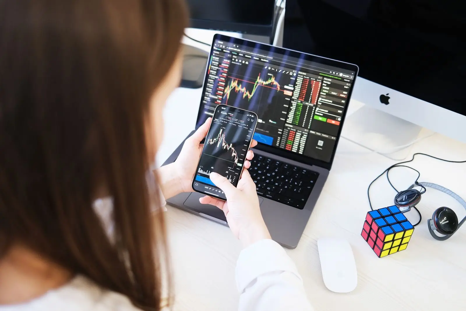 Trader memeriksa grafik di ponsel di samping laptop