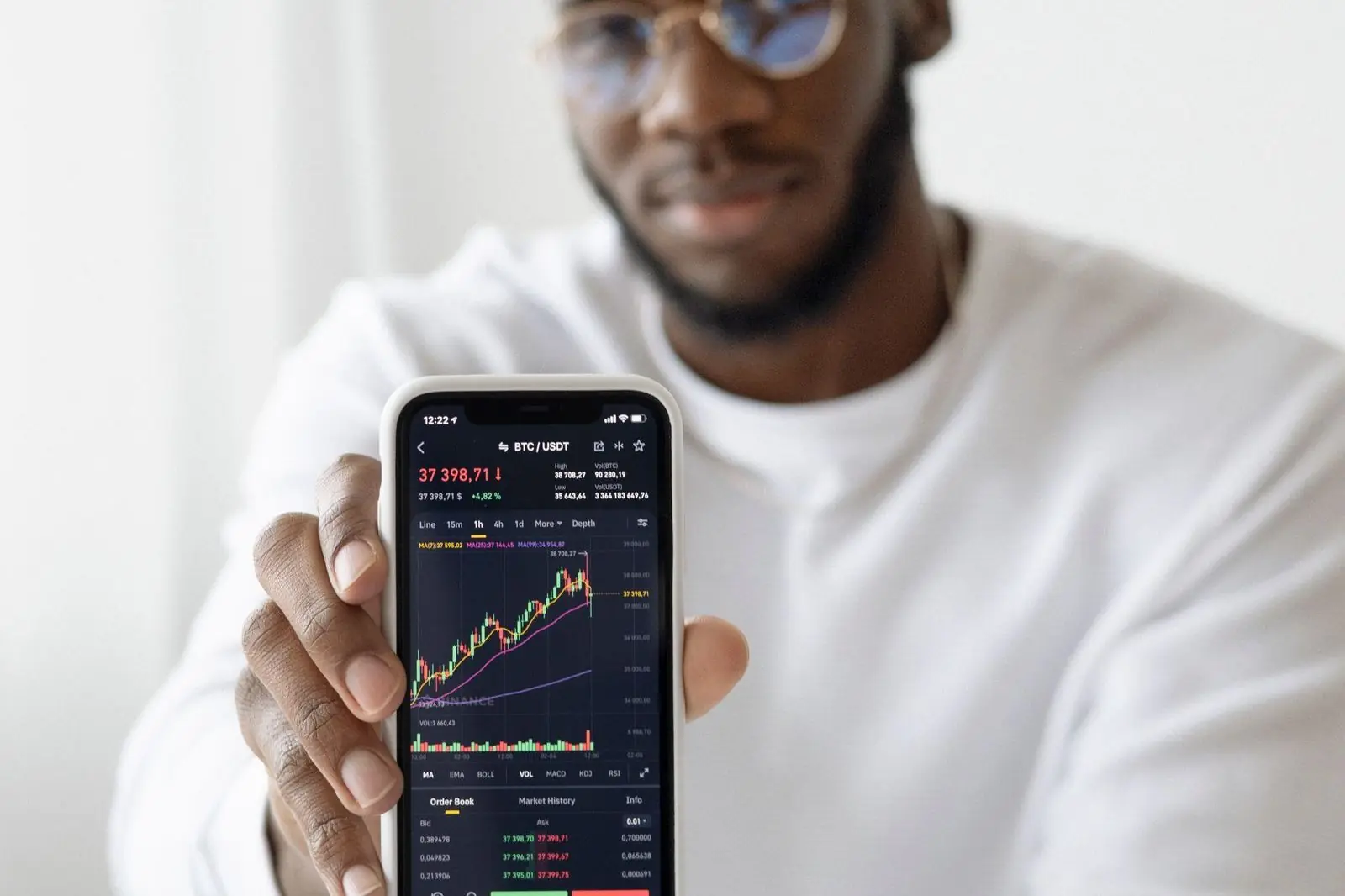 Pria menunjukkan grafik trading di ponsel pintarnya