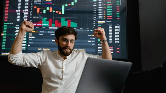 Trader at a desk reviewing market charts on two monitors